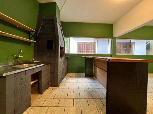 a large kitchen with green walls and a tile floor at Pousada VSC in São Francisco do Sul