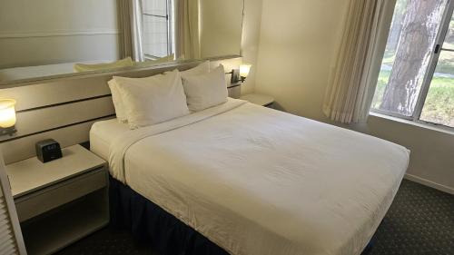 Habitación de hotel con cama con sábanas y almohadas blancas en Club Lakeridge, en Reno