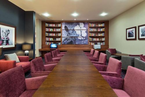 a long table in a library with pink chairs at Hampton by Hilton Luton Airport in Luton