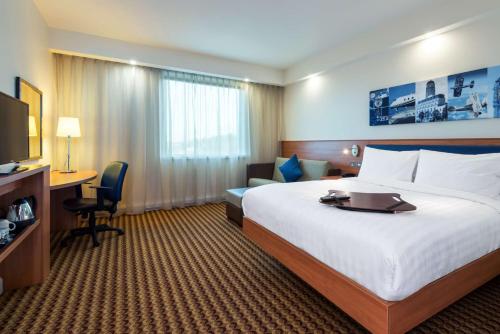a hotel room with a large bed and a desk at Hampton by Hilton Luton Airport in Luton