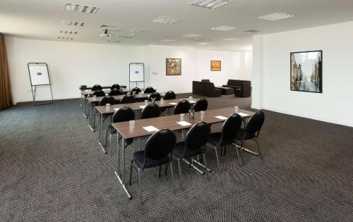 a conference room with tables and chairs and a couch at Hampton by Hilton Luton Airport in Luton