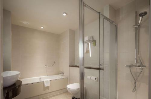 een badkamer met een douche, een toilet en een wastafel bij Hilton Garden Inn Luton North in Luton