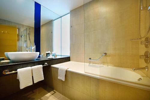 bagno con vasca e lavandino di Hilton Manchester Deansgate a Manchester