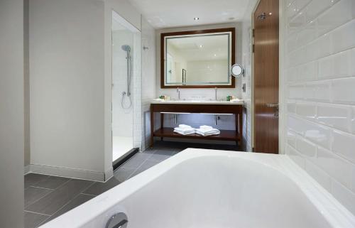 a bathroom with a tub and a sink and a mirror at Hilton Southampton - Utilita Bowl in Southampton