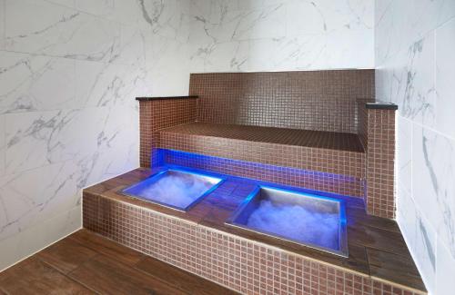 a jacuzzi tub in a brick shower with blue lighting at Hilton Southampton - Utilita Bowl in Southampton