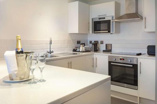 a white kitchen with two wine glasses on a counter at Hilton Southampton - Utilita Bowl in Southampton