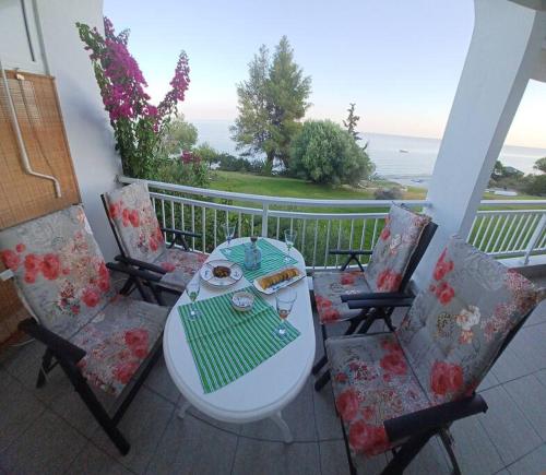 a table and chairs on a balcony with a view of the ocean at Απέραντο γαλάζιο Le grand blue in Mola Kalyva