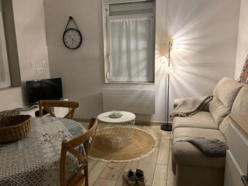 - un salon avec un canapé, une table et un réveil dans l'établissement Petite maison proche de Cambrai, à Iwuy
