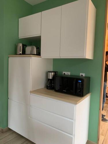 une cuisine avec des armoires blanches et un micro-ondes dans l'établissement Petite maison proche de Cambrai, à Iwuy