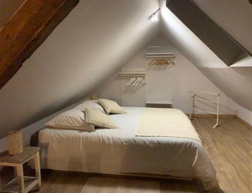 une chambre avec un lit blanc dans un grenier dans l'établissement Petite maison proche de Cambrai, à Iwuy