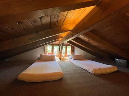 two beds in a attic room with wooden ceilings at Acogedora casa rural en la sierra de Madrid in Mataelpino