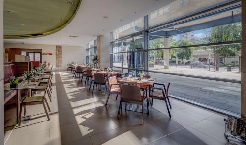ロンドンにあるヒルトン ロンドン カナリー ワーフのテーブルと椅子、大きな窓のあるレストラン