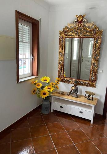 a bathroom with a mirror and flowers on a tiled floor at PESO RIVER HOUSE in Melgaço
