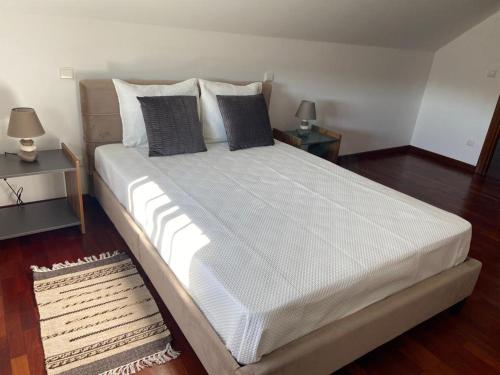 a large bed in a room with two night stands at PESO RIVER HOUSE in Melgaço