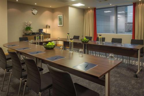 a conference room with a large wooden table and chairs at Hilton London Canary Wharf in London
