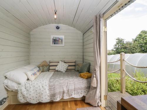 a bed in a small room with a porch at Flora's Hut in Liskeard