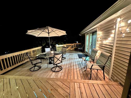 a deck with a table and chairs and an umbrella at WOW!! Ultimate Pocono Retreat, Hot Tub, Game Room, Deck, Lakes, Skiing, Pools in Long Pond