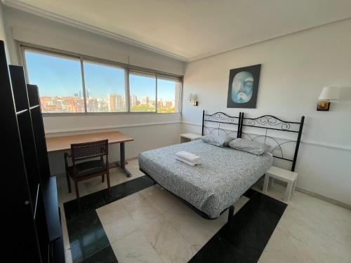 a bedroom with a bed and a desk and window at Pisos con piscina planta 20 y 13 super vistas in Madrid
