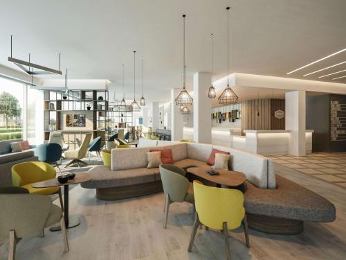 a living room with a couch and tables and chairs at Hampton By Hilton Edinburgh Airport in Ingliston