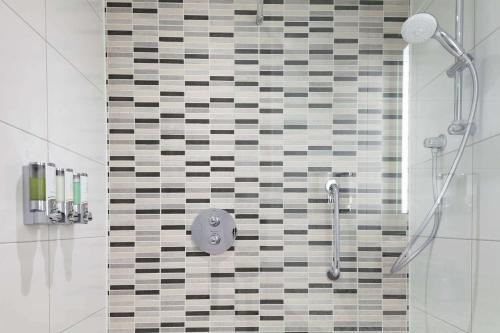 a shower in a bathroom with a tiled wall at Hampton By Hilton Edinburgh Airport in Ingliston