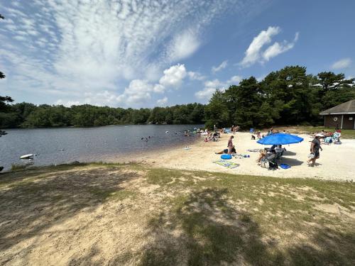 a group of people on a beach with a blue umbrella at WOW!! Ultimate Pocono Retreat, Hot Tub, Game Room, Deck, Lakes, Skiing, Pools in Long Pond