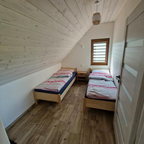two beds in a small room with a window at Markowe Domki in Ryn
