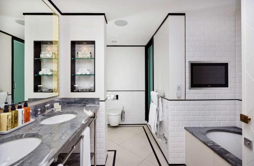 baño con 2 lavabos y TV de pantalla plana en The Waldorf Hilton, en Londres