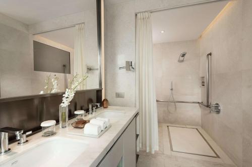 a white bathroom with a sink and a shower at Conrad Beijing by Hilton in Beijing