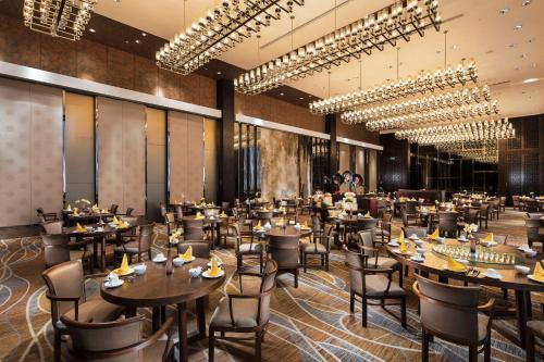 um restaurante com mesas, cadeiras e lustres em Hilton Guangzhou Tianhe - Free Canton Fair Shuttle Bus and Registration Counter em Guangzhou