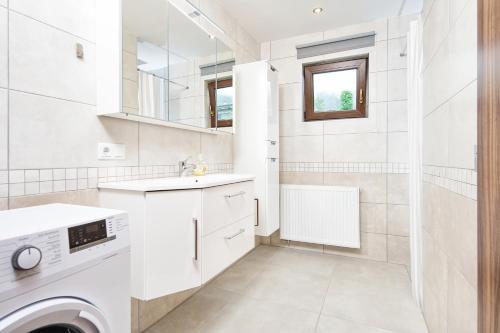 a white bathroom with a sink and a washing machine at Haus unter Gerlitzen in Bodensdorf