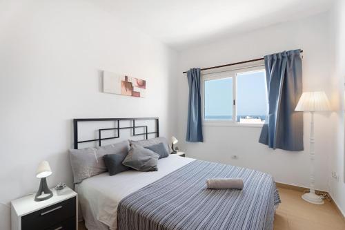 a bedroom with a bed with blue curtains and a window at Alcamar in Alcalá