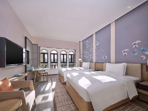 Doubletree By Hilton Yingde Resort في Yingde: غرفة فندقية بثلاث اسرة وتلفزيون بشاشة مسطحة
