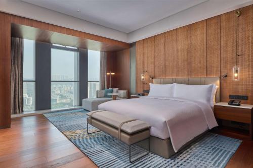 Hilton Chongqing Liangjiang New Area في تشونغتشينغ: غرفة نوم بسرير كبير وأريكة