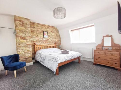 um quarto com uma parede de tijolos e uma cama e uma cadeira azul em Entire 3 bedroom house 5 minutes from the beach em Kent