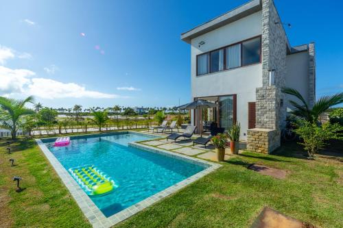 een achtertuin met een zwembad en een huis bij Reserva Sauípe - Casa 224 in Mata de Sao Joao