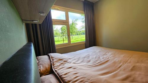 um quarto com uma cama e uma janela em Huisje Weideblik em Doornspijk