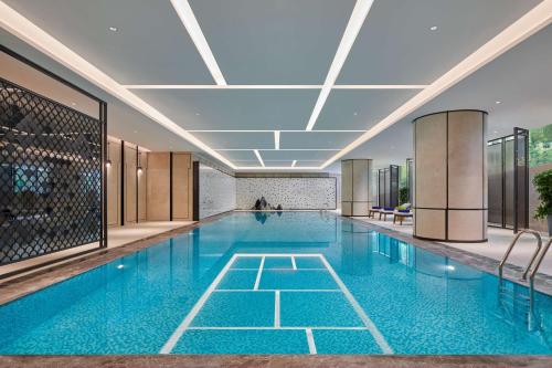 a swimming pool with blue water in a building at Hilton Changsha Riverside in Changsha