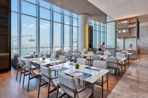 comedor con mesas y sillas y ventanas grandes en Hilton Changsha Riverside en Changsha