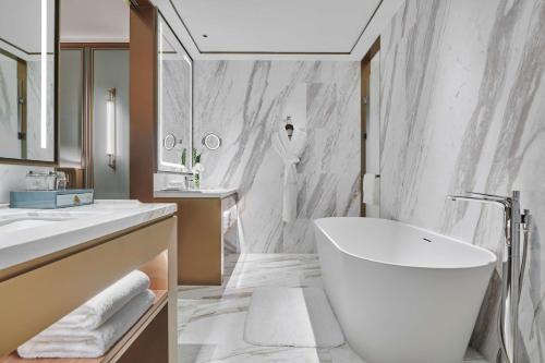 a bathroom with a large white tub and a sink at Hilton Changsha Riverside in Changsha