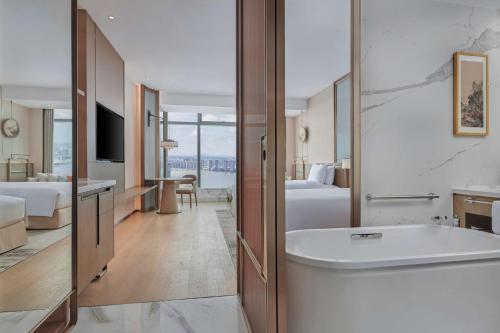 a large bathroom with a tub and a bedroom at Hilton Changsha Riverside in Changsha