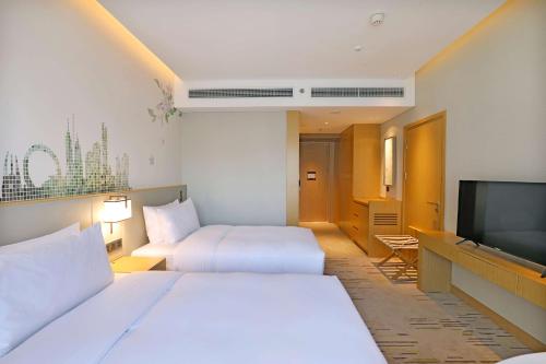 a hotel room with two beds and a flat screen tv at Hilton Garden Inn Changzhou Xinbei in Changzhou