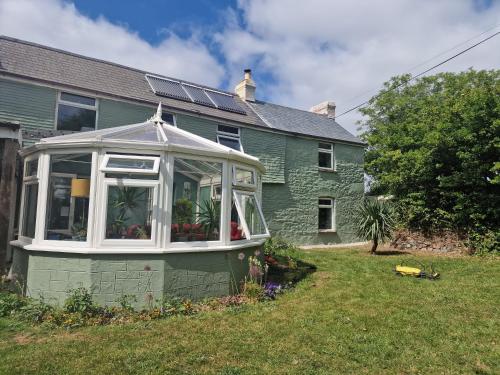 una casa verde con un salón acristalado en el patio en Goonearl Simply Stay en Scorrier