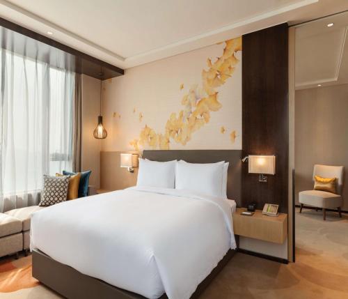 een groot wit bed in een hotelkamer bij Hilton Garden Inn Dandong in Dandong