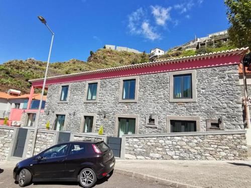 a black car parked in front of a stone building at Chalé Esmeralda - Charming Studios in Calheta Beach in Calheta