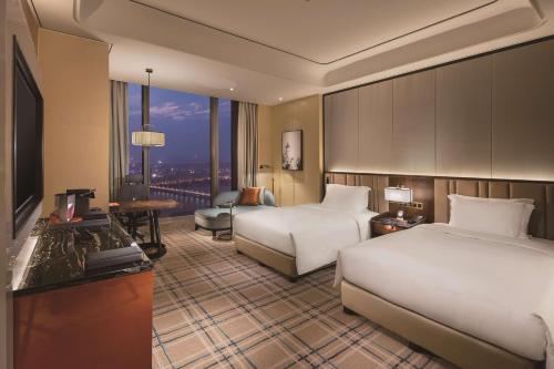 a hotel room with two beds and a desk at Hilton Fuzhou in Fuzhou