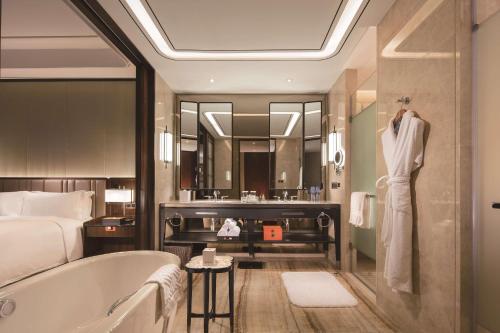 Hilton Fuzhou في فوتشو: حمام مع حوض استحمام وسرير وحوض استحمام