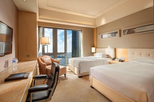 a large hotel room with two beds and a desk at Hilton Dalian in Dalian