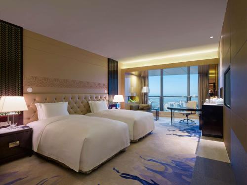 two beds in a hotel room with a view at Hilton Haikou in Haikou