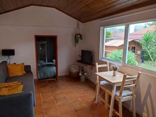 sala de estar con sofá, mesa y ventana en Casinha do pinhal, en Colares