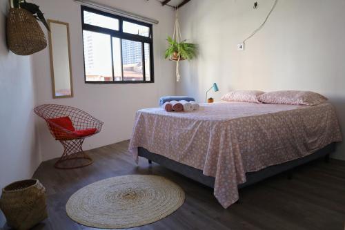a bedroom with a bed and a red chair at CASA IRACEMAR in Fortaleza